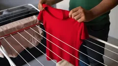 Rood t-shirt ophangen aan droogrek voor het drogen van was in huis