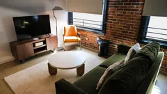 Moderne woonkamer met groene bank en bakstenen muur