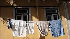 Kleding hangt buiten aan een waslijn bij een gebouw